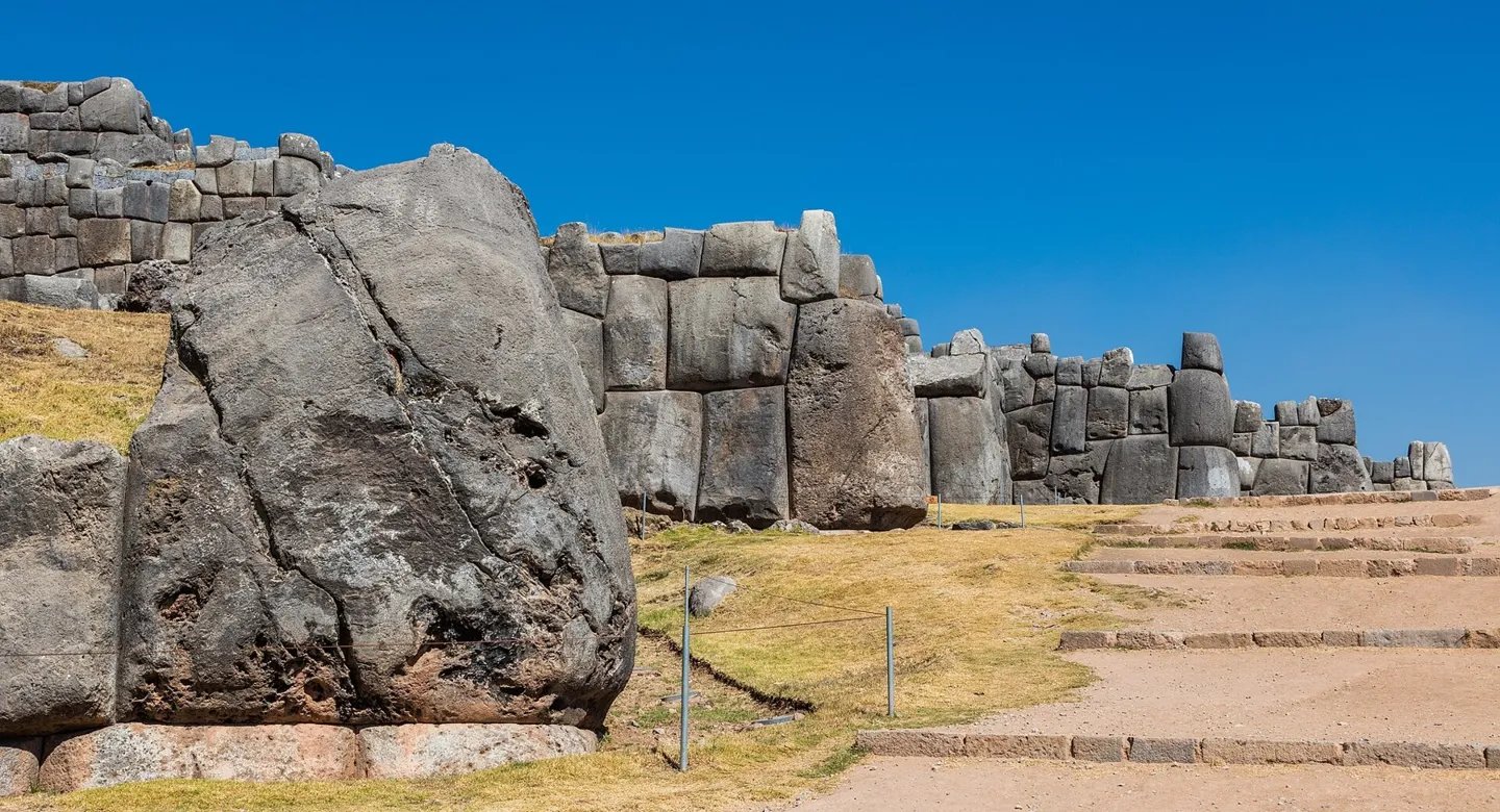 View of a row of corners of the walls of Saksaywaman, a citadel on the northern outskirts of the city of en:Cusco, historic capital of the Inca Empire, today Peru. The first sections of the citadel were first built by the Killke culture about 1100 and expanded by the Inca from the 13th century. The dry stone walls are composed of huge stones, which boulders are carefully cut by workers to fit them together extremely tightly without mortar.