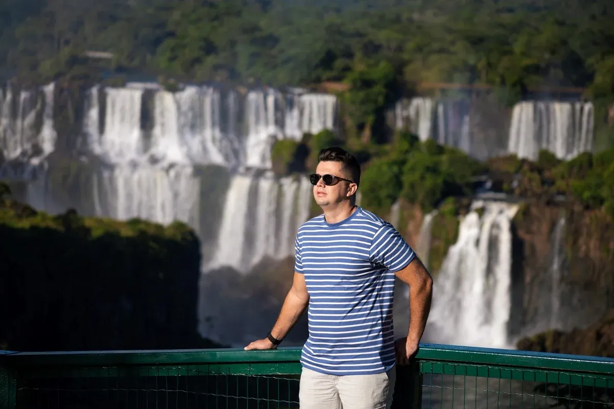 Retrato de visitante de camisa listrada diante das Cataratas do Iguaçu