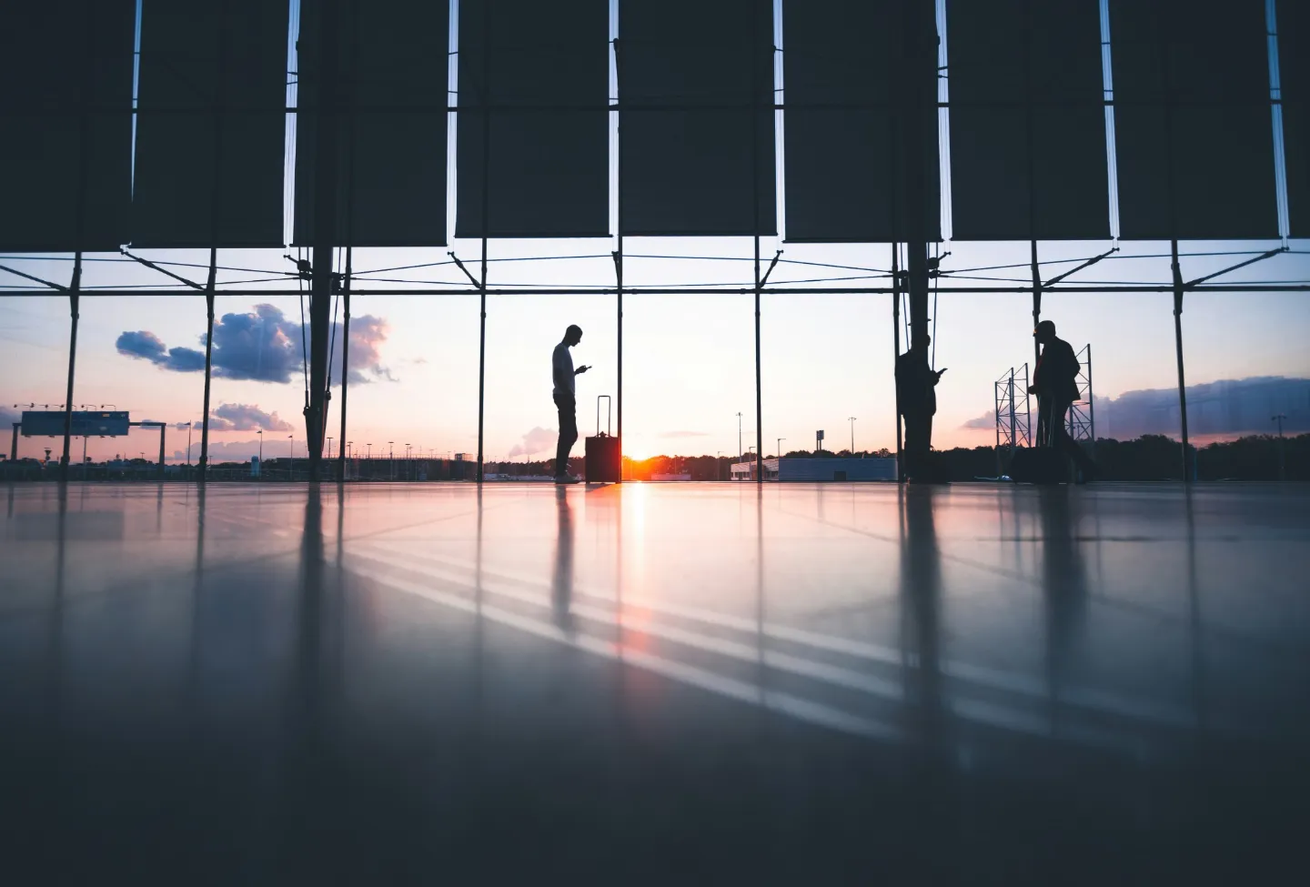 Viajantes com bagagens em um terminal de aeroporto ao pôr do sol